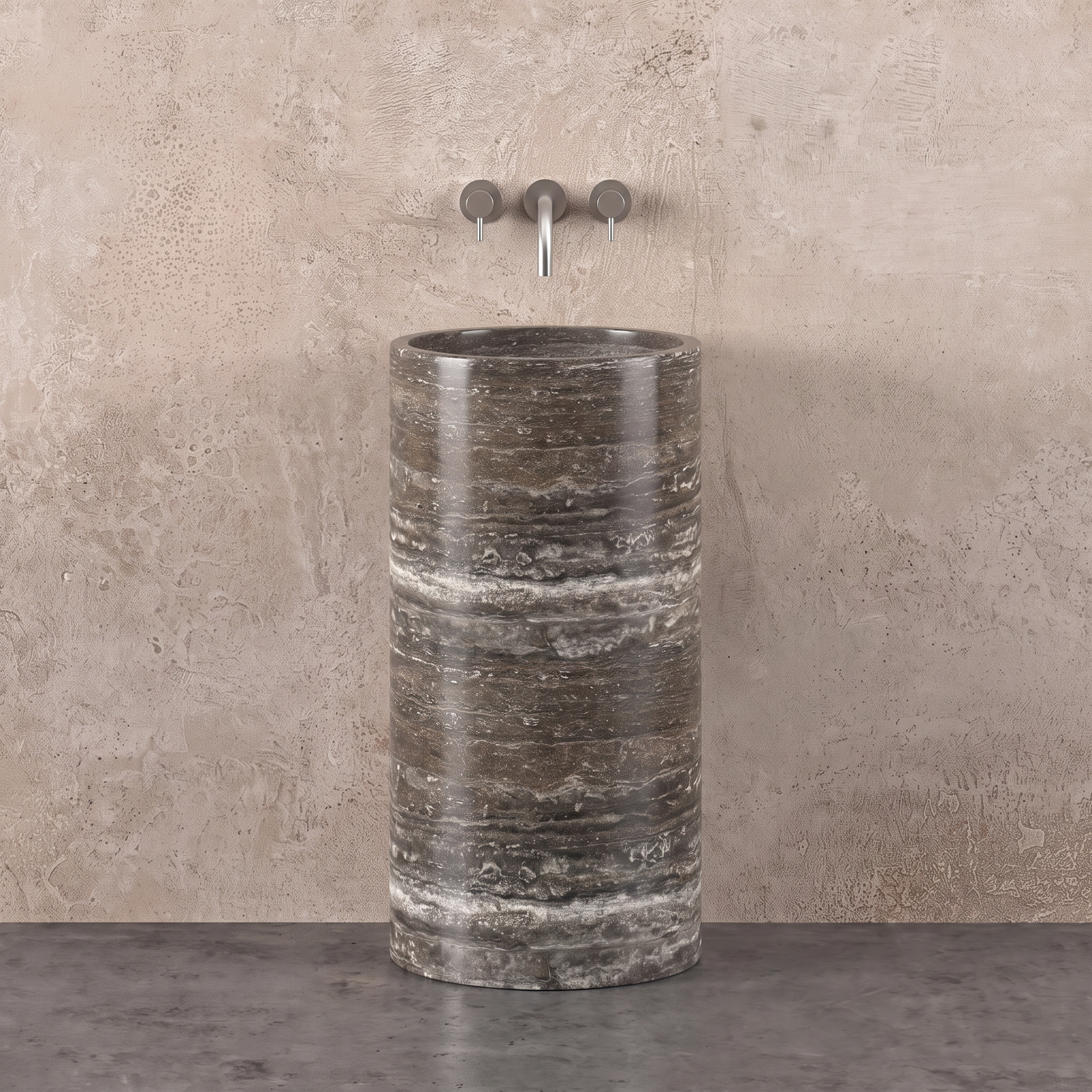 A cylindrical stone bathroom sink with a silver travertine, paired with a matching three-hole wall-mounted faucet against a textured beige plaster wall.