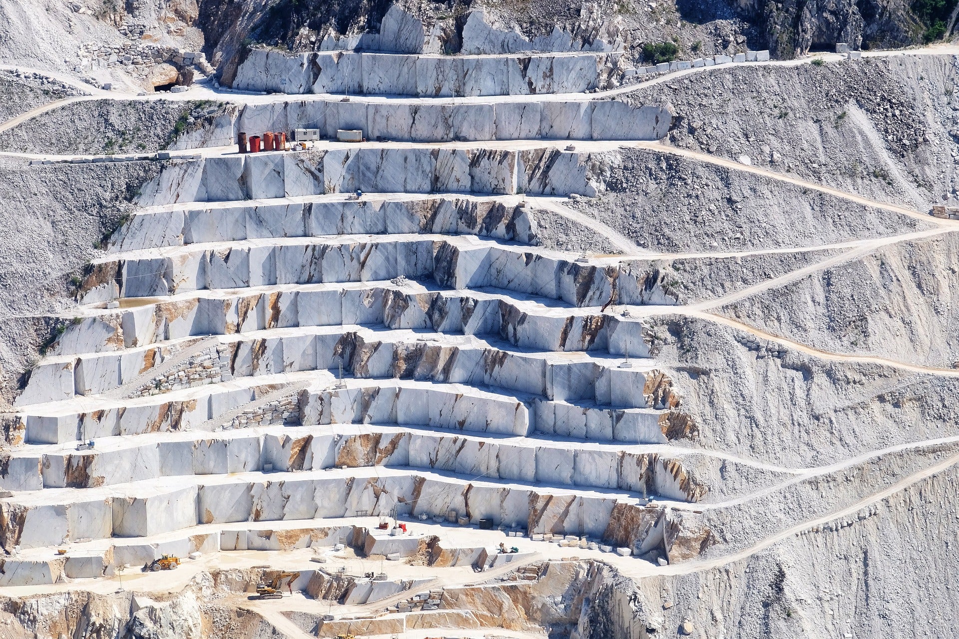 A marble quarry with large white blocks being ethically extracted in a mountainous landscape.