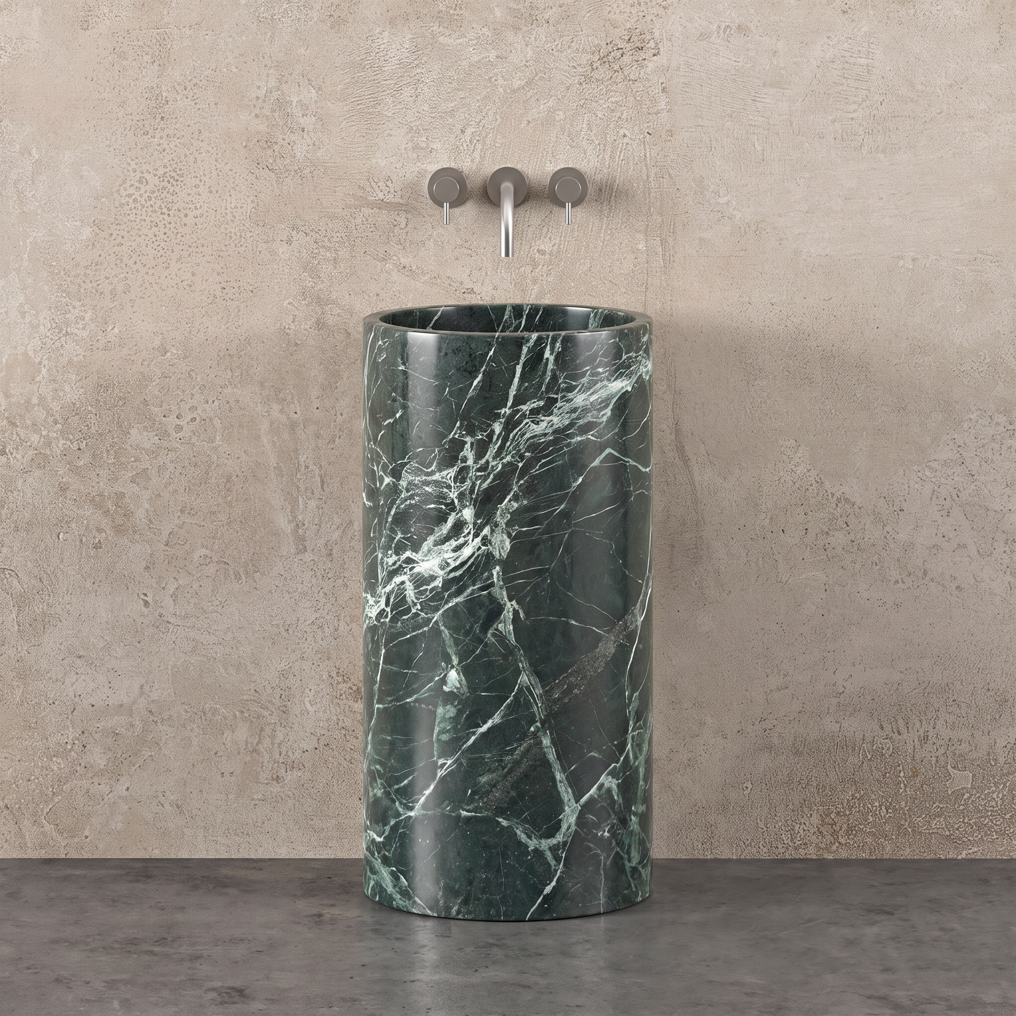 A cylindrical verde alpi marble pedestal sink with white veining, set against a textured beige plaster wall 